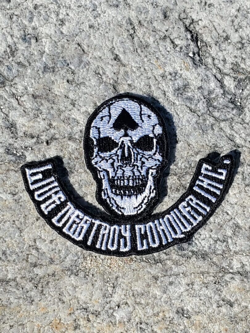 A patch of skull with the words " live destroy conquer life ".