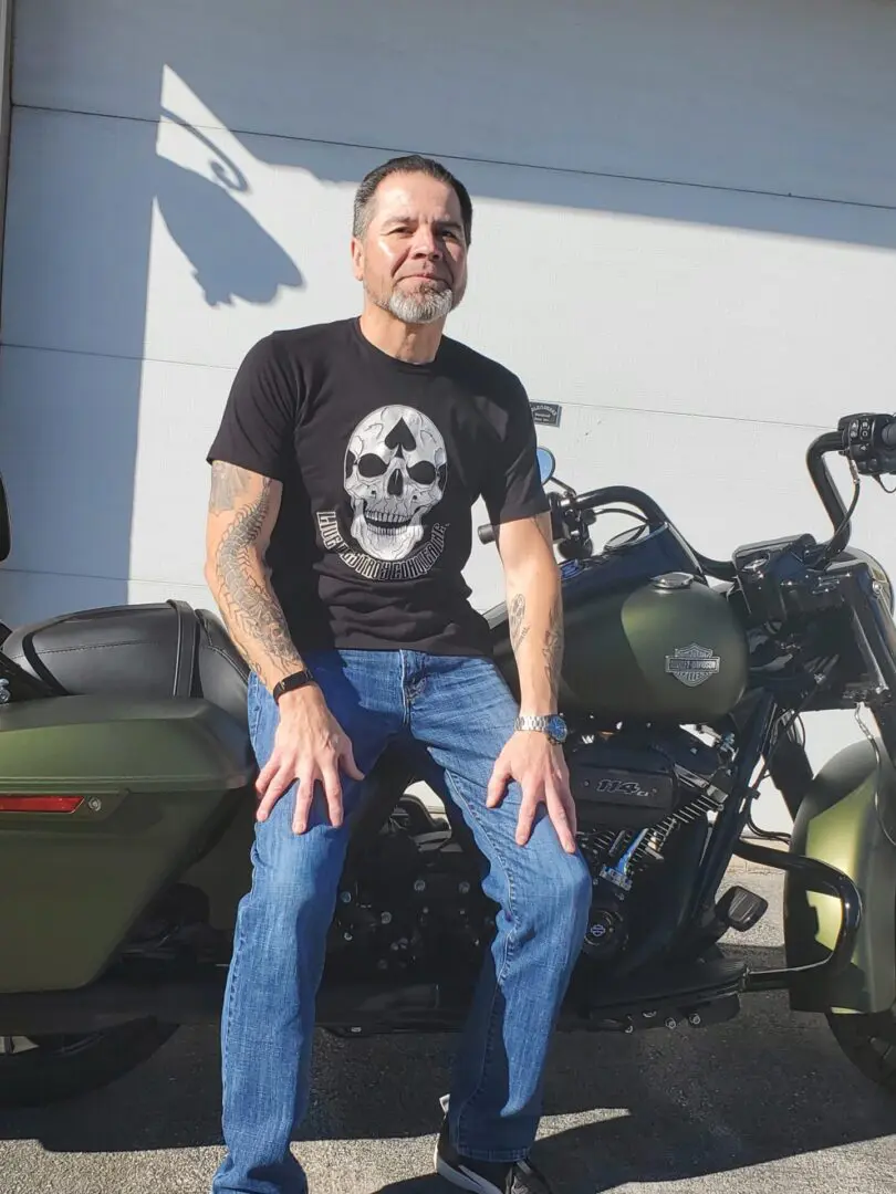 A man sitting on the ground next to two motorcycles.